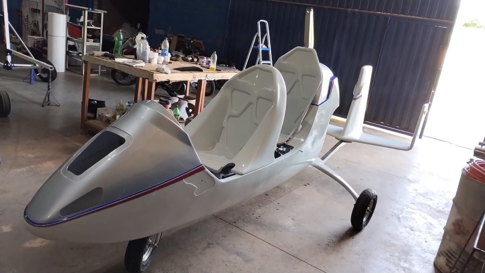 Girocóptero prata em montagem no galpão da Pegasus, com assentos e cauda posicionados