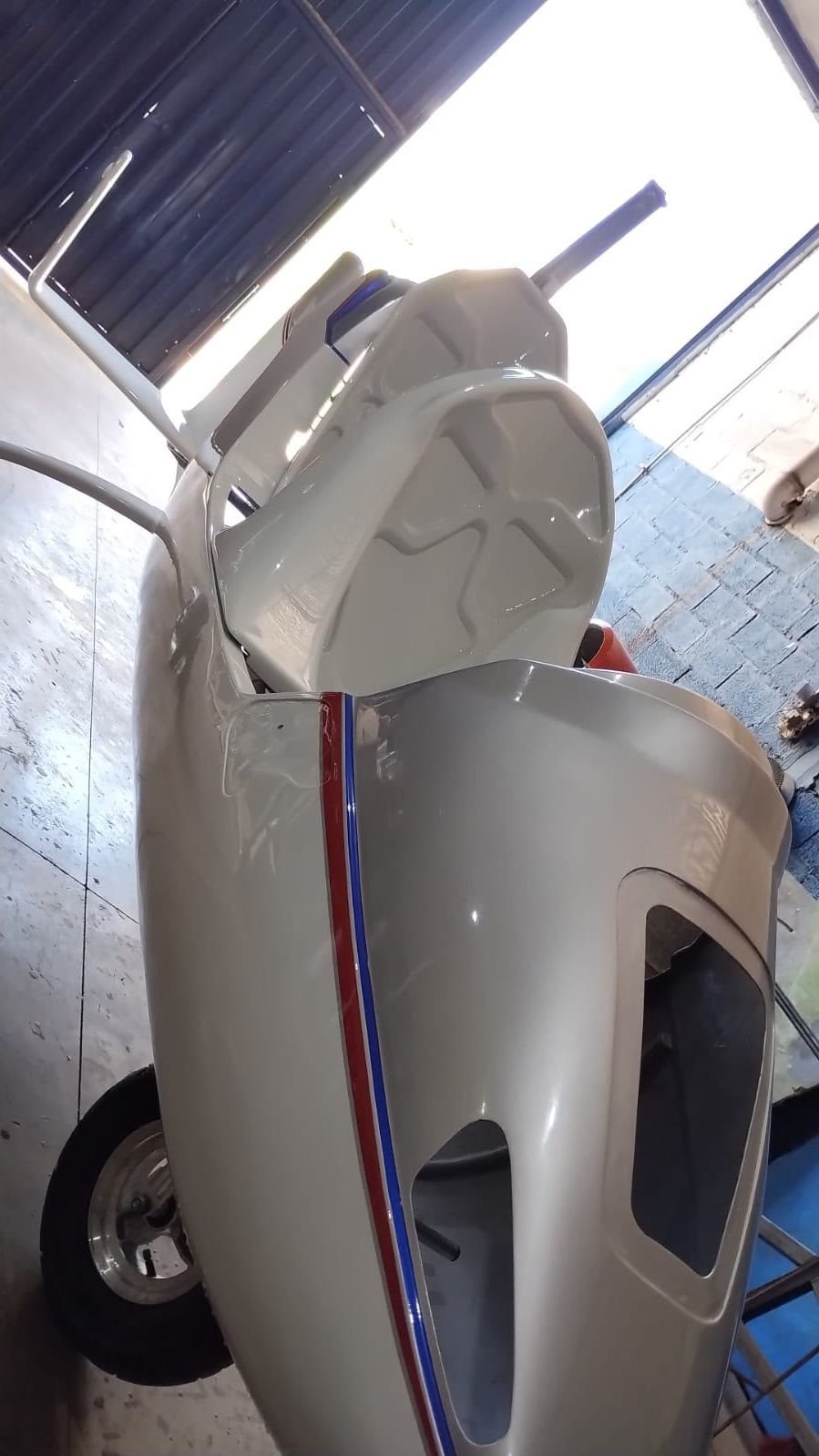 Detalhe da carenagem lateral de girocóptero prata com faixa azul e vermelha
